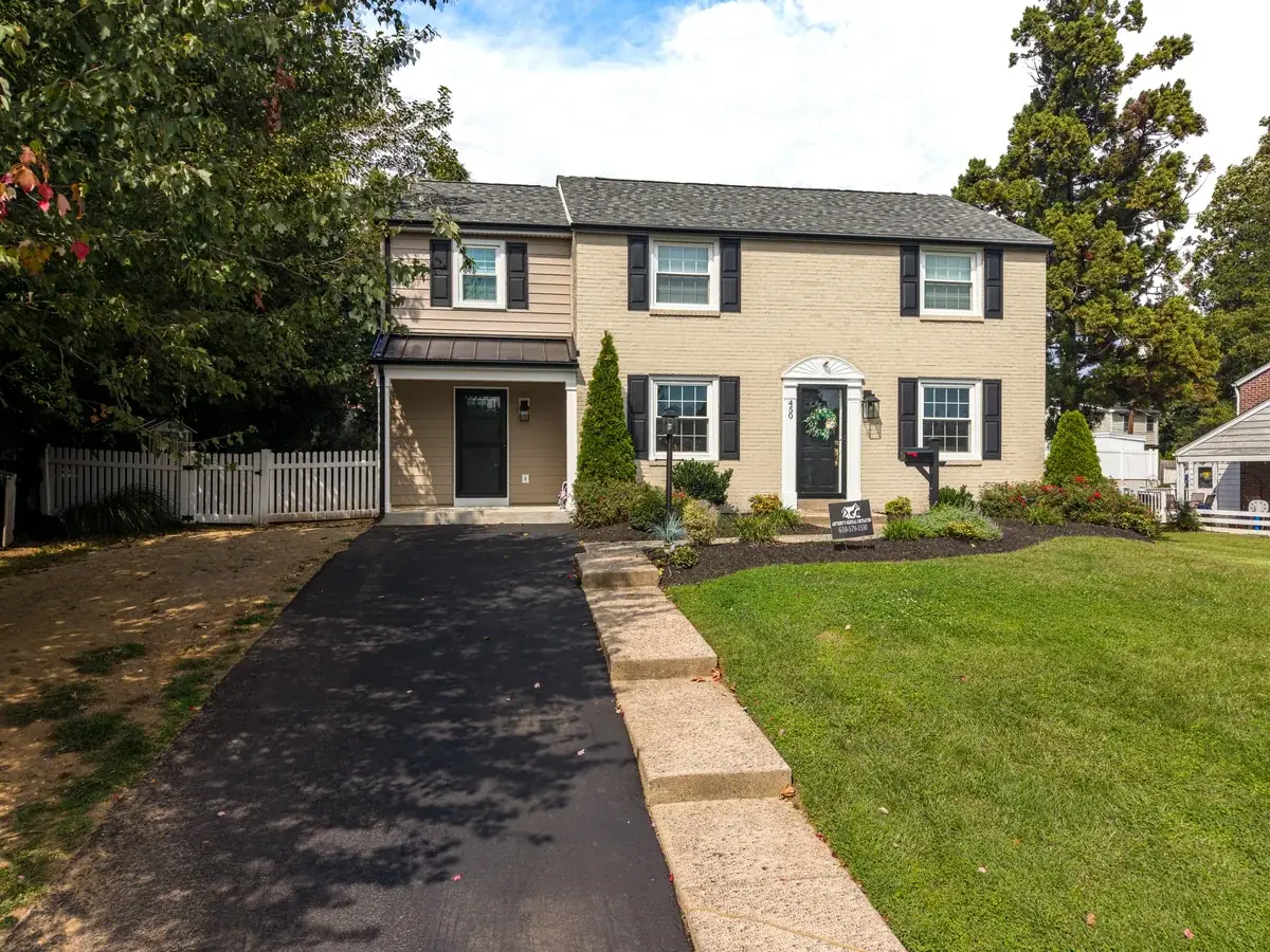 Aerial view of a tan two-story home, driveway, and landscaped front yard.