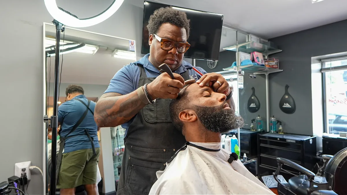 A barber gives a customer a close shave inside a neighborhood shop.