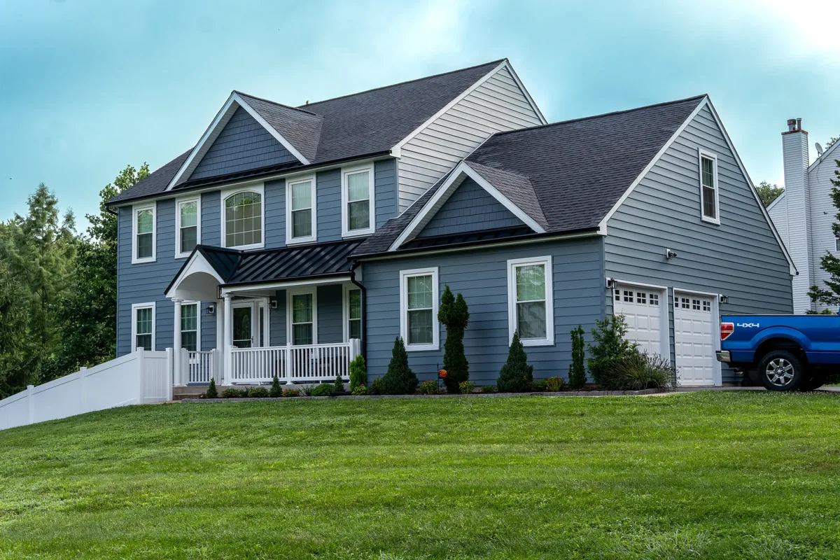 A blue-gray home with updated siding, white trim, and a front lawn.