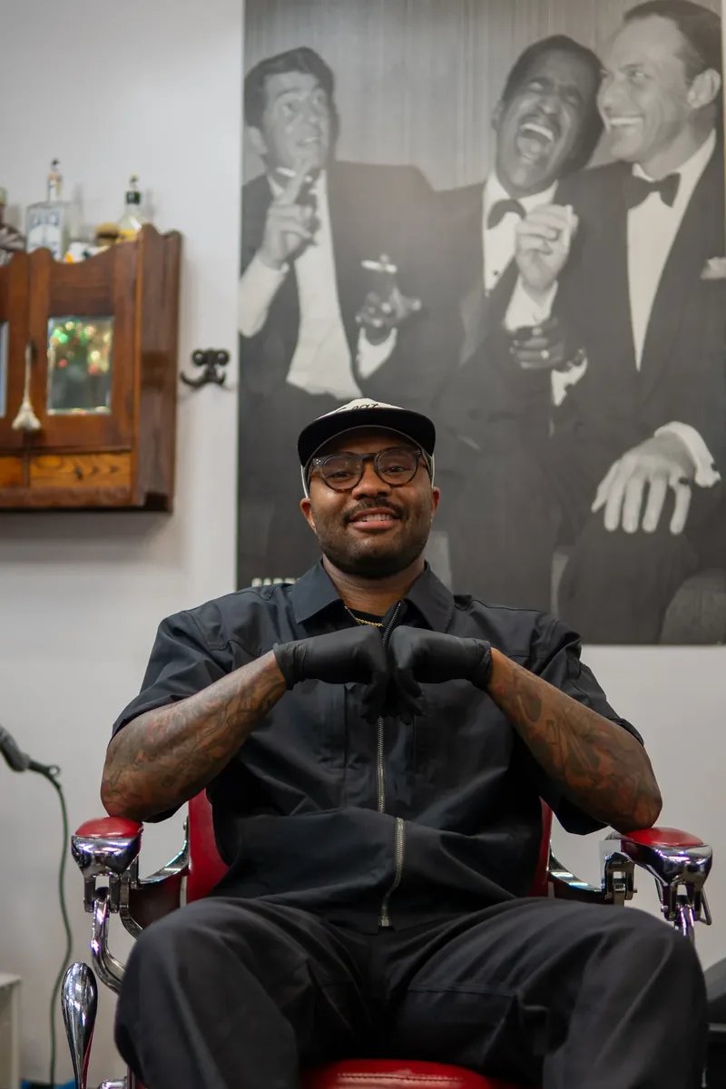 A barber stands inside Giovanni’s Barbershop.