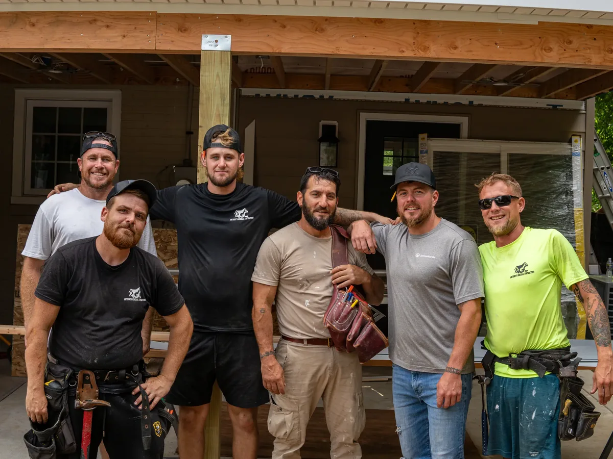 The construction crew stands together at a residential job site.