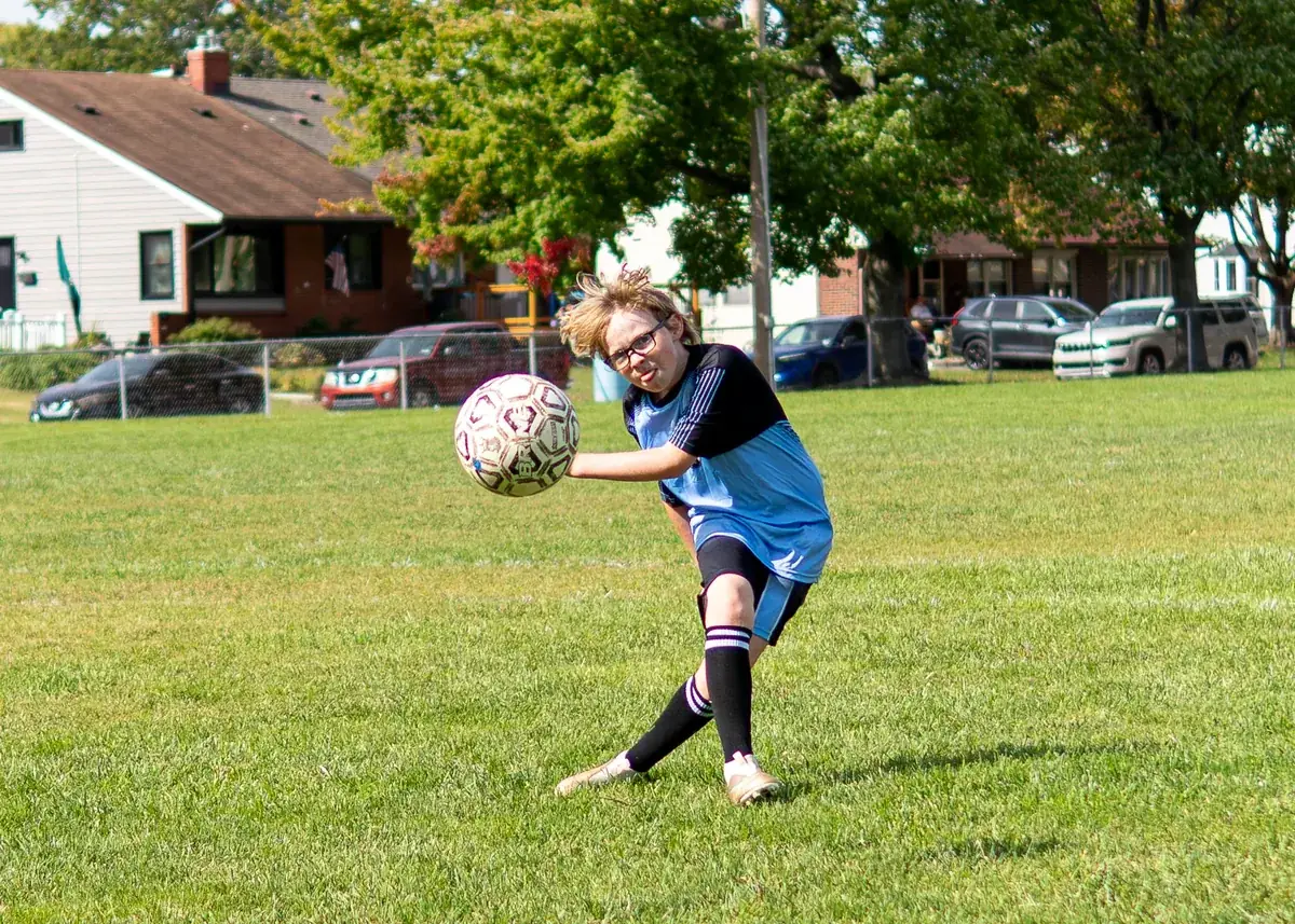 A soccer player moves toward the ball on a grass field.